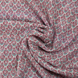 Textured muslin printed with purple and turquoise floral medallions on a white background