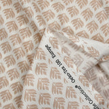 Popelín revestido con estampado vegetal beige sobre fondo blanco roto