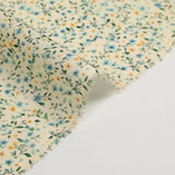 Digital printed cotton voile with yellow flowers and green foliage on a cream background