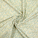 Digital printed cotton voile with yellow flowers and green foliage on a cream background