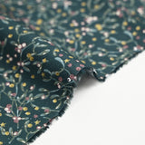 Cotton poplin printed with sprigs of mistletoe and gold stars on a green background