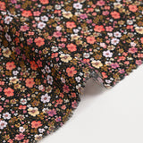 Digital printed cotton voile meadow of small orange and butter yellow flowers on a black background