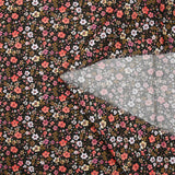 Digital printed cotton voile meadow of small orange and butter yellow flowers on a black background