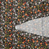 Digital printed cotton voile meadow of small green and orange flowers on a black background