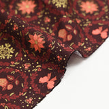Cotton poplin printed with poinsettias and orange bows on a brown background