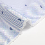 Popelina de algodón estampada con finas rayas azules y hojas azul marino