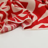 Jersey de polyester imprimé formes de fleurs écru fond rouge