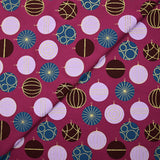 Popelina de algodón estampada con bolas festivas y destellos dorados sobre fondo morado