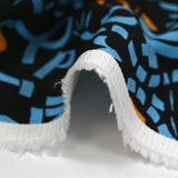 Sergé de coton imprimé graffitis bleu et orange fond noir
