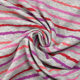 Sudadera de peluche a rayas rojas, rosas y violetas con fondo gris jaspeado
