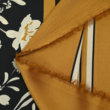 Satin polyester twill printed with ecru flowers and ocher border, black background