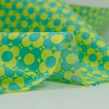 Coated poplin printed with fields of flowers, green lemon background