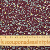 Cotton poplin printed with sprigs of mistletoe and gold stars on a wine-colored background