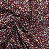 Cotton poplin printed with sprigs of mistletoe and gold stars on a wine-colored background
