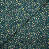 Cotton poplin printed with sprigs of mistletoe and gold stars on a green background
