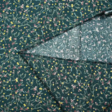 Cotton poplin printed with sprigs of mistletoe and gold stars on a green background