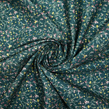 Cotton poplin printed with sprigs of mistletoe and gold stars on a green background
