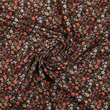 Digital printed cotton voile meadow of small orange and butter yellow flowers on a black background