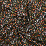Digital printed cotton voile meadow of small green and orange flowers on a black background