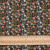 Digital printed cotton voile meadow of small green and orange flowers on a black background