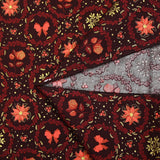 Cotton poplin printed with poinsettias and orange bows on a brown background