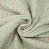 Tweed de laine mélangée confettis rose et bleu fond vert
