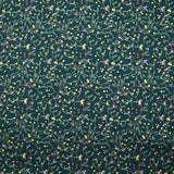 Cotton poplin printed with sprigs of mistletoe and gold stars on a green background